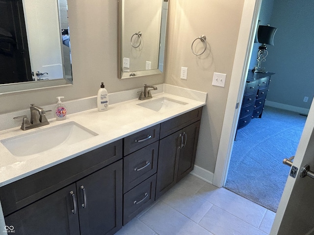 full bathroom with a sink, tile patterned floors, double vanity, and baseboards