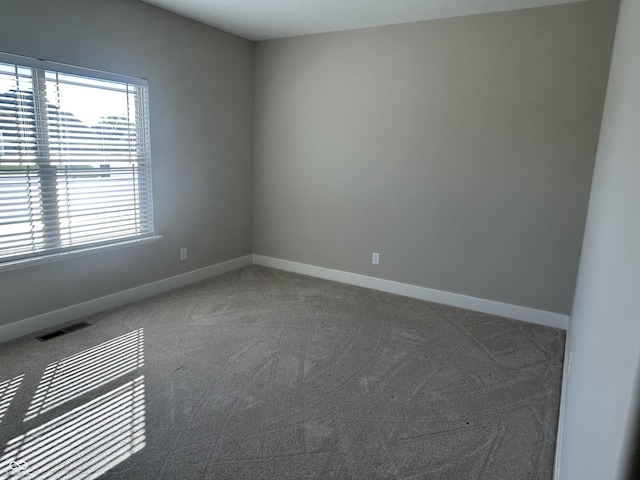 carpeted empty room with visible vents, baseboards, and plenty of natural light