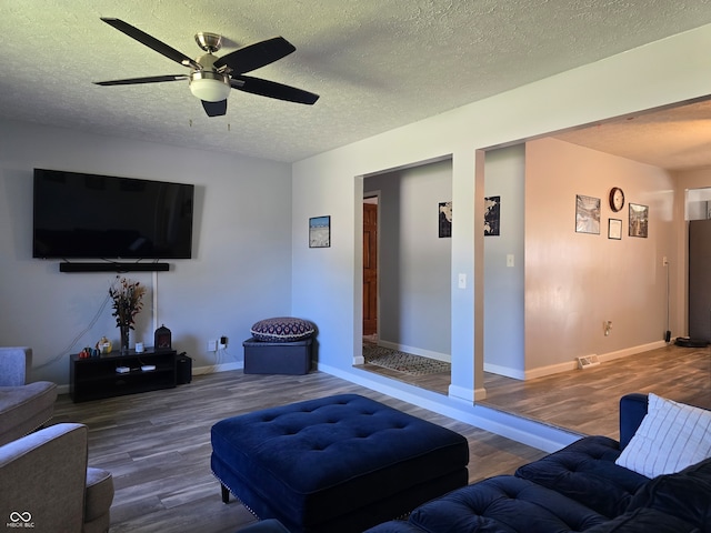 living room featuring a textured ceiling, hardwood / wood-style flooring, and ceiling fan