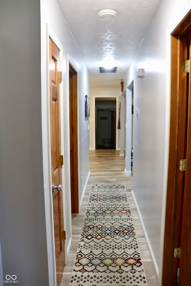 hall featuring a textured ceiling and light wood-type flooring