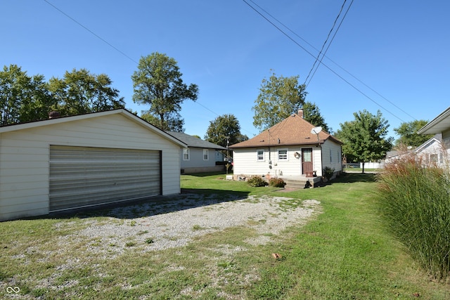 rear view of property with a lawn, an outbuilding, a chimney, and a garage