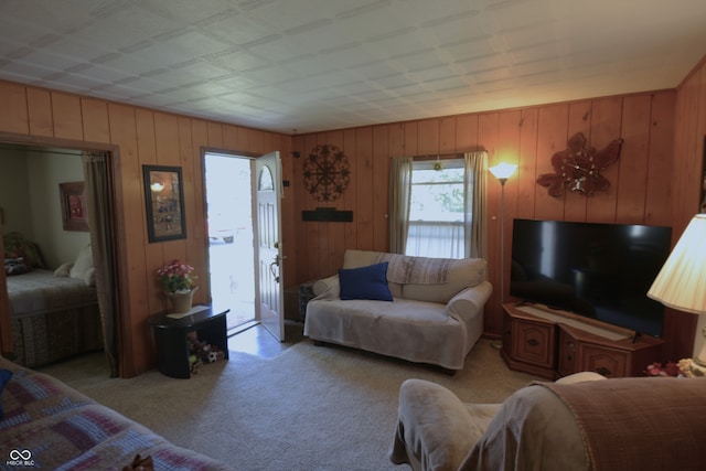 carpeted living room featuring wooden walls