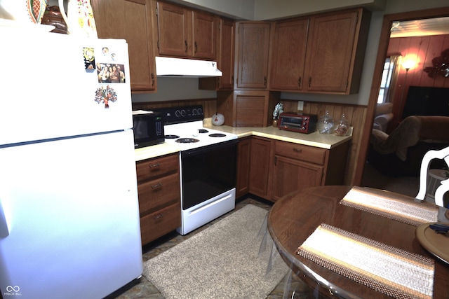 kitchen featuring range hood, range with electric stovetop, light countertops, freestanding refrigerator, and black microwave