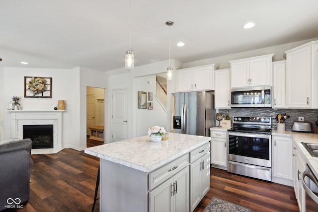 kitchen featuring appliances with stainless steel finishes, hanging light fixtures, a center island, and dark wood-type flooring