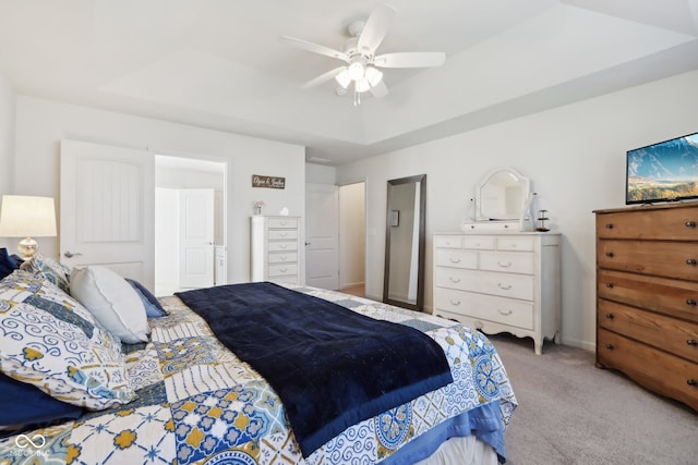 bedroom featuring ceiling fan, light colored carpet, and a tray ceiling