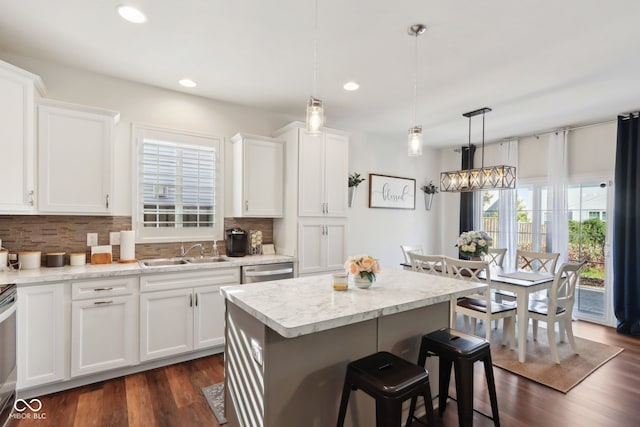 kitchen with white cabinets, dark wood-type flooring, pendant lighting, and sink