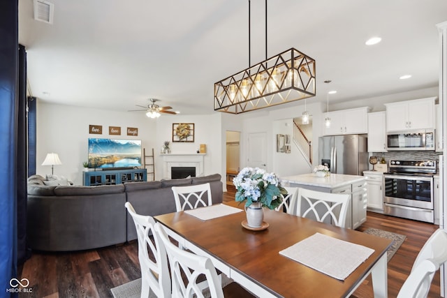 dining area with ceiling fan and dark wood-type flooring