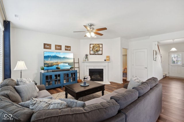 living room with a high end fireplace, ceiling fan, and dark hardwood / wood-style flooring