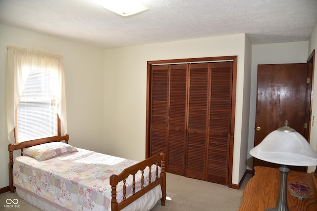 bedroom featuring a textured ceiling, a closet, and light colored carpet