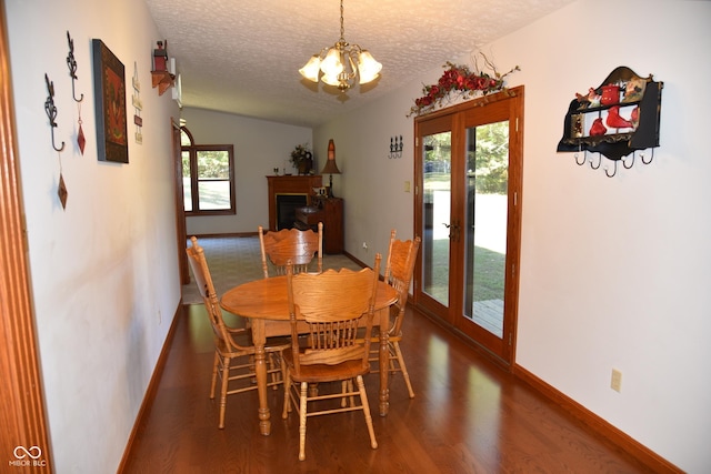 dining space with a wealth of natural light, wood finished floors, and an inviting chandelier