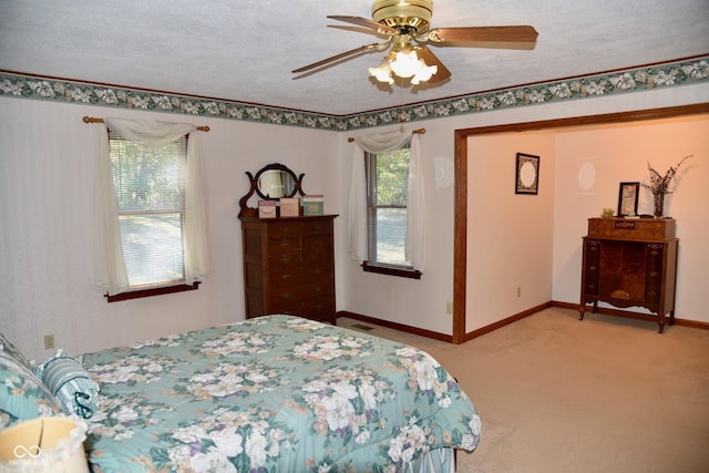 bedroom featuring light carpet, a ceiling fan, baseboards, and a textured ceiling