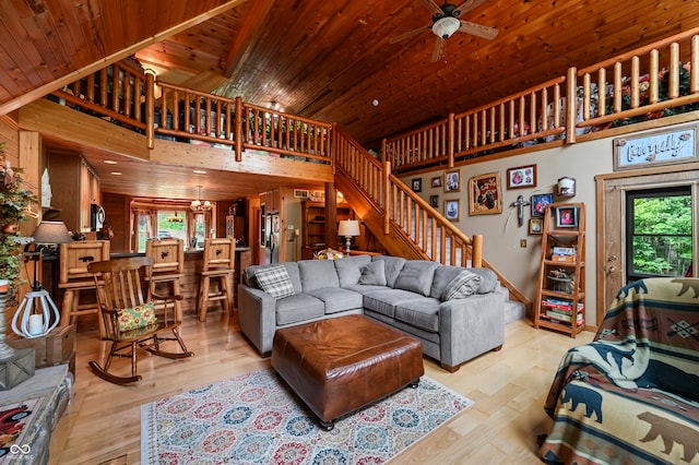 living room with a wealth of natural light, a towering ceiling, light hardwood / wood-style floors, and wooden ceiling