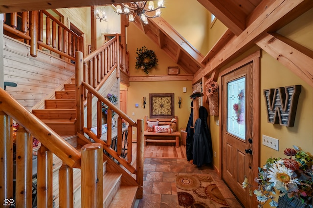 entrance foyer featuring beamed ceiling, wood walls, hardwood / wood-style flooring, a notable chandelier, and a towering ceiling