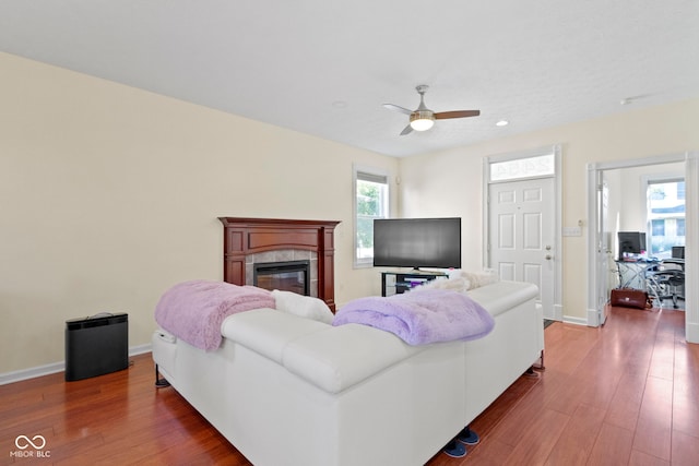 living room featuring hardwood / wood-style flooring, a tiled fireplace, and ceiling fan