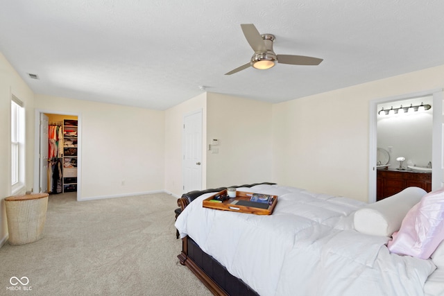 bedroom featuring ceiling fan, light colored carpet, a closet, and a walk in closet