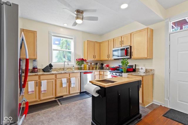 kitchen with light brown cabinetry, appliances with stainless steel finishes, sink, and ceiling fan