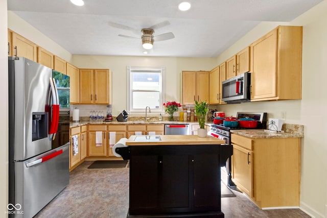 kitchen with stainless steel appliances, light brown cabinets, a center island, and ceiling fan