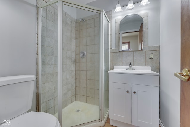 bathroom featuring toilet, vanity, tile walls, and a shower with door