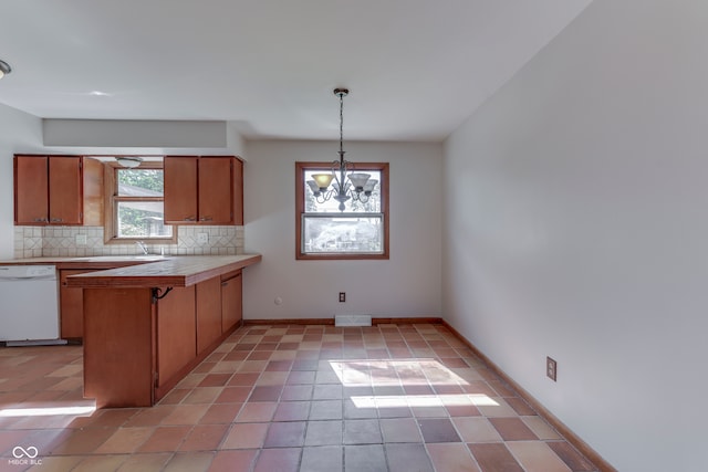 kitchen featuring tile countertops, backsplash, white dishwasher, pendant lighting, and a notable chandelier