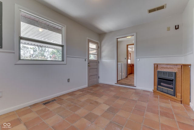 unfurnished living room with washer / clothes dryer, light tile patterned floors, and a fireplace