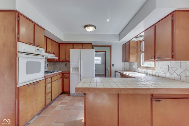 kitchen with white appliances, tile countertops, sink, and kitchen peninsula