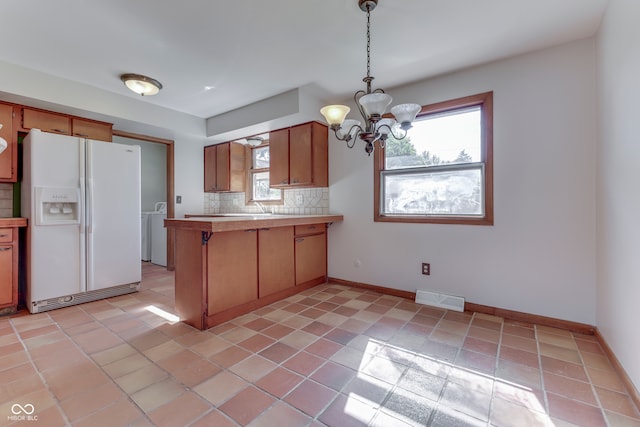 kitchen featuring white fridge with ice dispenser, tasteful backsplash, a chandelier, and plenty of natural light