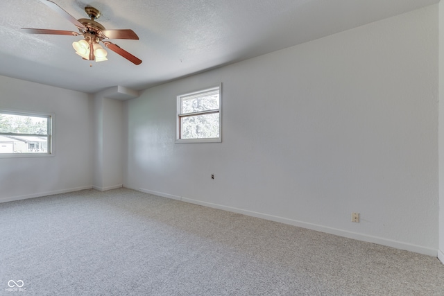 carpeted spare room with ceiling fan, a textured ceiling, and plenty of natural light