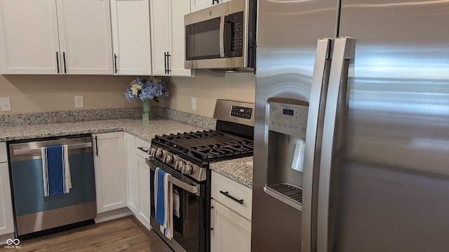 kitchen featuring light stone counters, light hardwood / wood-style flooring, white cabinets, and appliances with stainless steel finishes