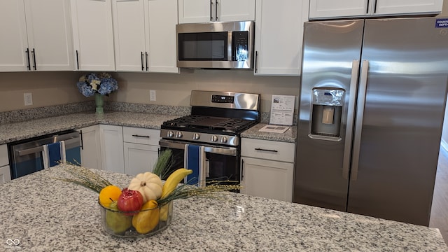 kitchen featuring white cabinetry, stainless steel appliances, and light stone countertops