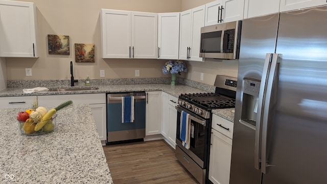 kitchen featuring light stone counters, stainless steel appliances, and white cabinets