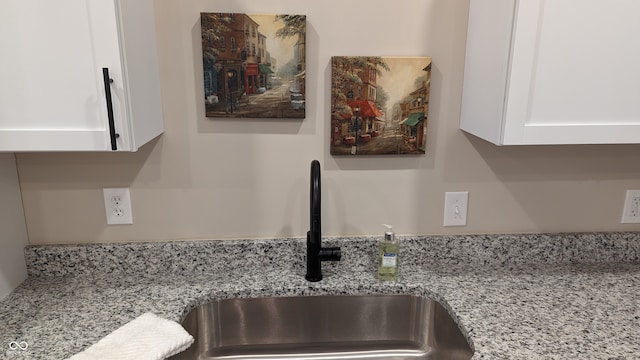 details featuring light stone counters, sink, and white cabinets