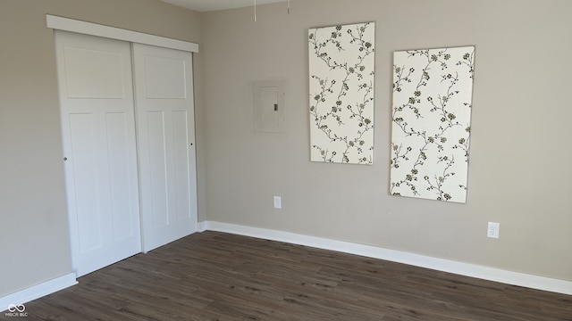 unfurnished bedroom featuring dark wood-type flooring, electric panel, and a closet