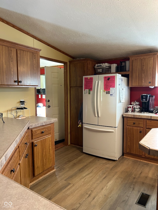 kitchen with white fridge, ornamental molding, a textured ceiling, and hardwood / wood-style flooring