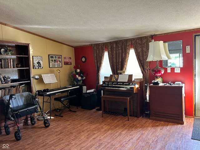 misc room with wood-type flooring, a textured ceiling, and crown molding