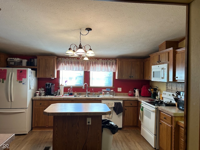 kitchen featuring white appliances, light hardwood / wood-style flooring, a notable chandelier, and sink