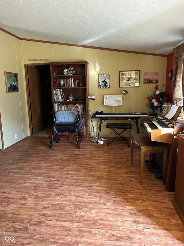 miscellaneous room with ornamental molding, light wood-type flooring, a textured ceiling, and vaulted ceiling