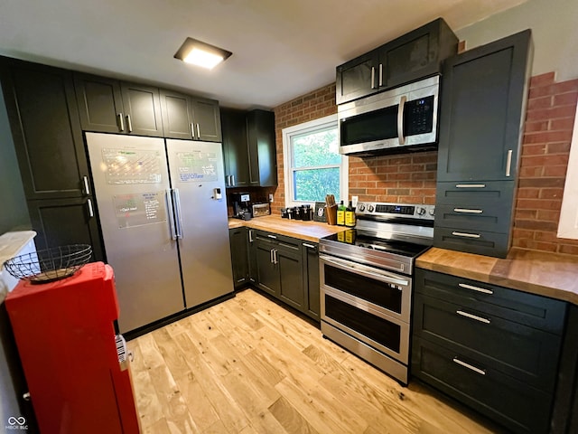 kitchen with decorative backsplash, appliances with stainless steel finishes, light hardwood / wood-style flooring, and wood counters