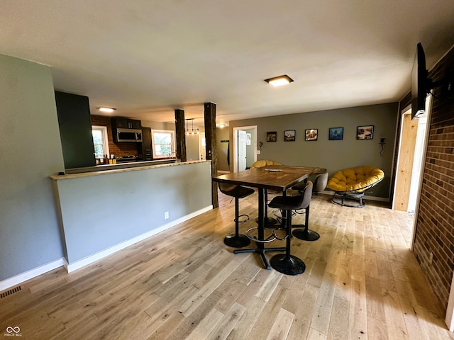 dining space featuring brick wall and light wood-type flooring