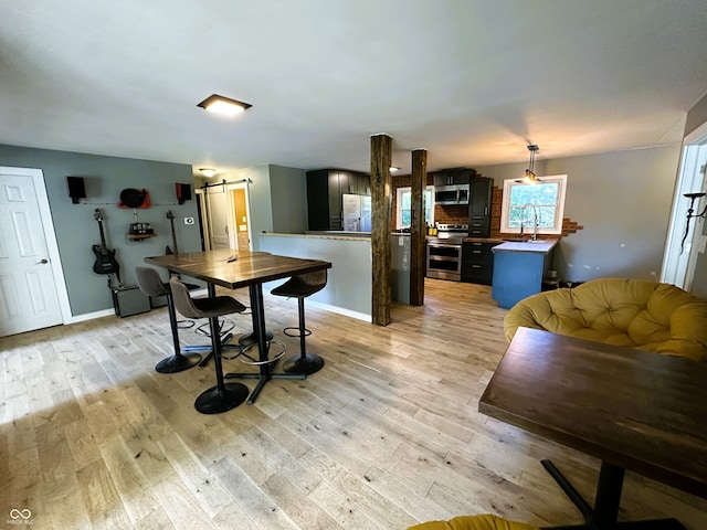 dining space featuring sink, a barn door, and light hardwood / wood-style floors