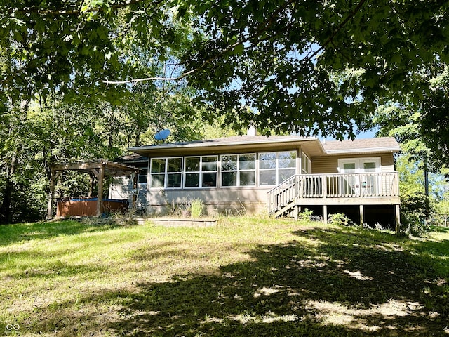 rear view of property with a yard, a pergola, and a deck