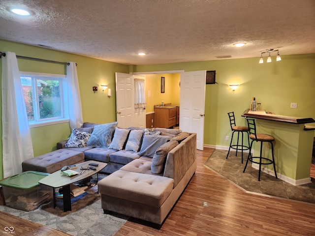 living room featuring a textured ceiling, indoor bar, and hardwood / wood-style flooring