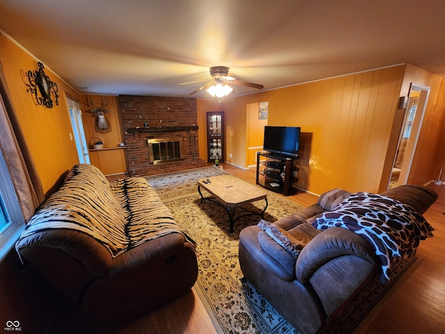 living room with a brick fireplace, ceiling fan, and hardwood / wood-style flooring