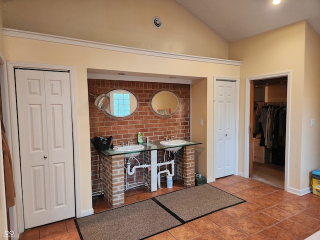 interior space with brick wall, lofted ceiling, and sink