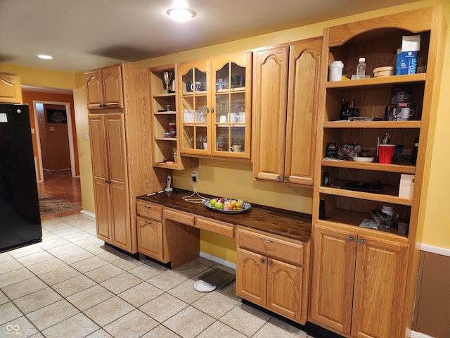 kitchen featuring black fridge, light tile patterned flooring, and built in desk