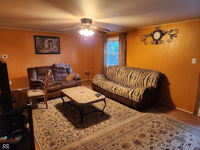 living room featuring wood-type flooring, wood walls, and ceiling fan