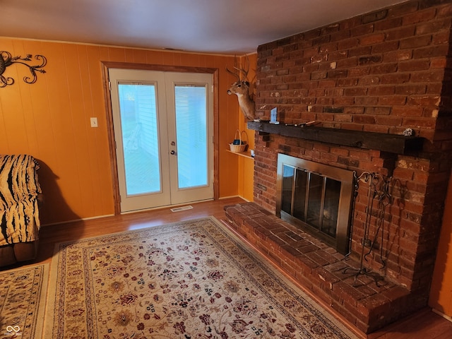 unfurnished living room with a brick fireplace, wood walls, and hardwood / wood-style floors