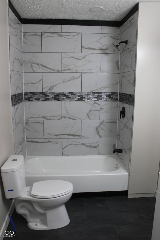 bathroom with a textured ceiling, toilet, and tiled shower / bath