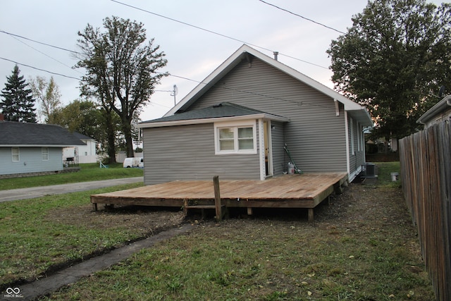 back of property with central AC unit, a lawn, and a deck