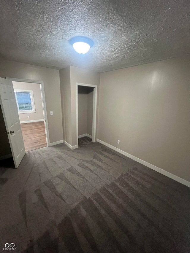 unfurnished bedroom with a textured ceiling, carpet flooring, and a closet