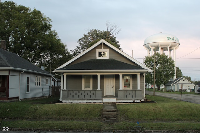 bungalow with covered porch and a yard